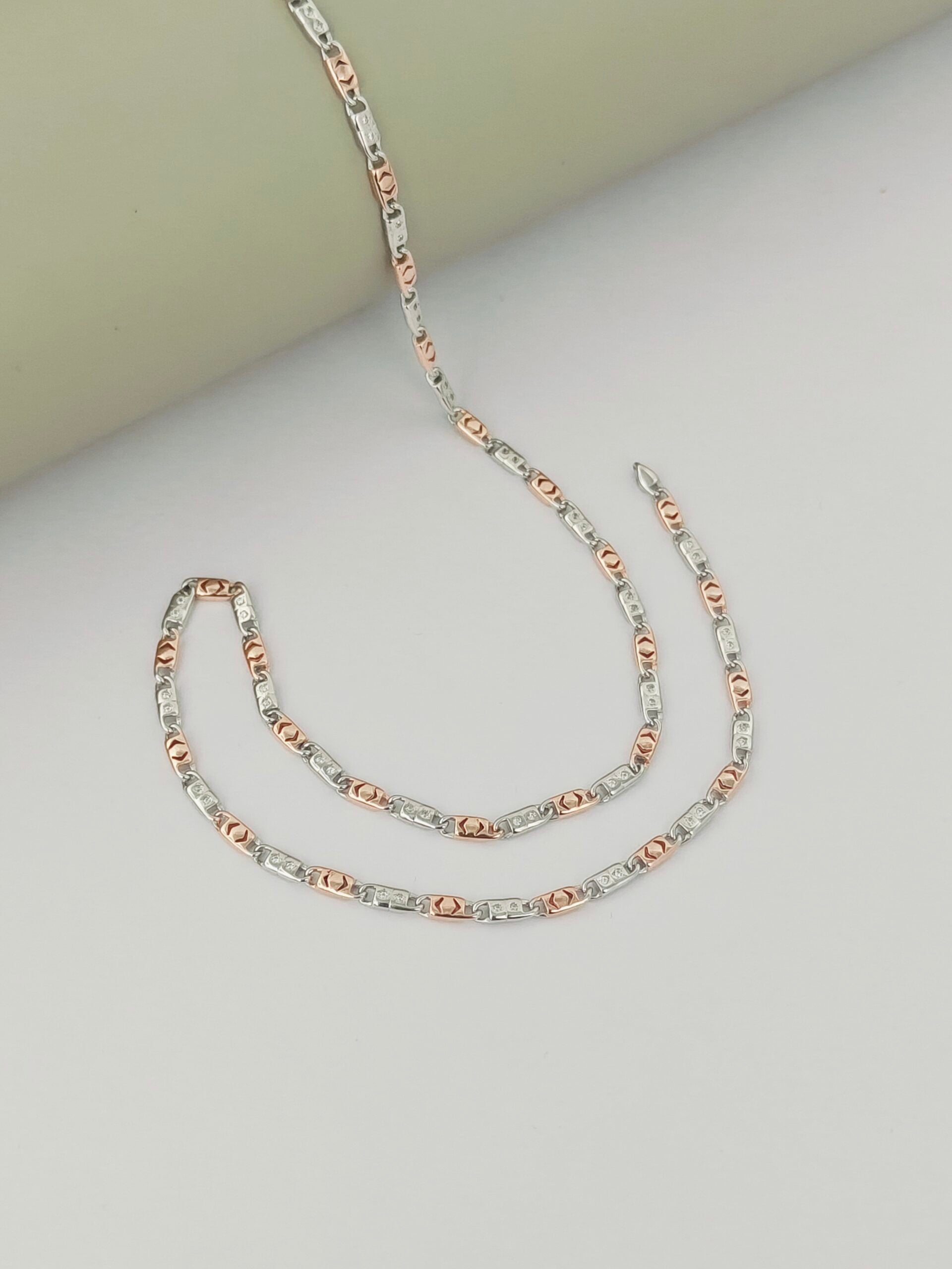 Two-layered necklace with rose gold and silver chain on a light gray background